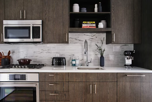 Gourmet kitchens feature gas cooktops and Bosch appliances with quartz counters and a marble backsplash.