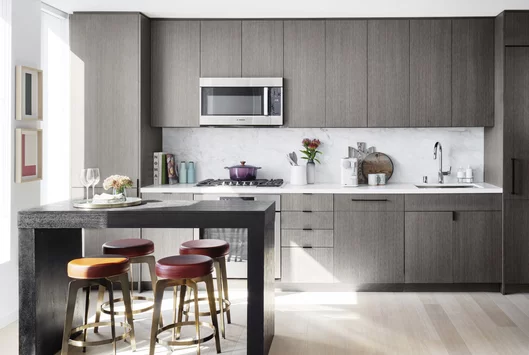 Open kitchens with custom grey-oak cabinetry, Bosch appliances, white Caesarstone counters and a Calacatta Caldia marble slab backsplash.