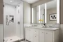 Luxuriate in master baths featuring white natural stone vanity, Kohler fixtures and accessories in polished chrome, and natural stone tile floor in white herringbone tile.