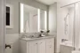 Luxuriate in master baths featuring white natural stone vanity, Kohler fixtures and accessories in polished chrome, and natural stone tile floor in white herringbone tile.