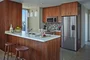 Aspire to culinary greatness in The Emerson's open kitchen with breakfast bar, featuring professional stainless steel appliances from Fisher & Paykel and Bosch, set against walnut cabinetry with Caesarstone counters and a full-height, tiled backsplash.