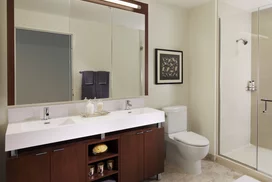 Custom bathrooms with polished natural stone floors, custom walnut vanities, and oversized showers