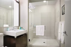 Custom bathrooms with polished natural stone floors, custom walnut vanities, and oversized showers