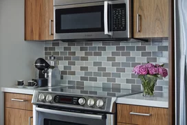 Aspire to culinary greatness in The Emerson's open kitchen with breakfast bar, featuring professional stainless steel appliances from Fisher & Paykel and Bosch, set against walnut cabinetry with Caesarstone counters and a full-height, tiled backsplash.