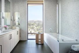 Luxe baths include a custom grey oak bathroom vanity with marble counters, frameless glass-enclosed showers with marble tile wet walls and oversized porcelain tile flooring.