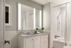 Luxuriate in master baths featuring white natural stone vanity, Kohler fixtures and accessories in polished chrome, and natural stone tile floor in white herringbone tile.