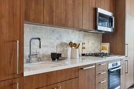 White quartz kitchen counter with a full-height Carrara marble tile backsplash