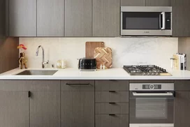 Open kitchens with custom grey-oak cabinetry, Bosch appliances, white Caesarstone counters and a Calacatta Caldia marble slab backsplash.