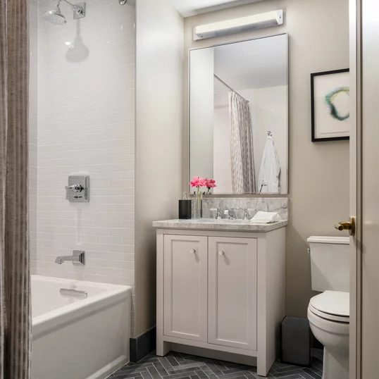 Luxuriate in master baths featuring white natural stone vanity, Kohler fixtures and accessories in polished chrome, and natural stone tile floor in white herringbone tile.